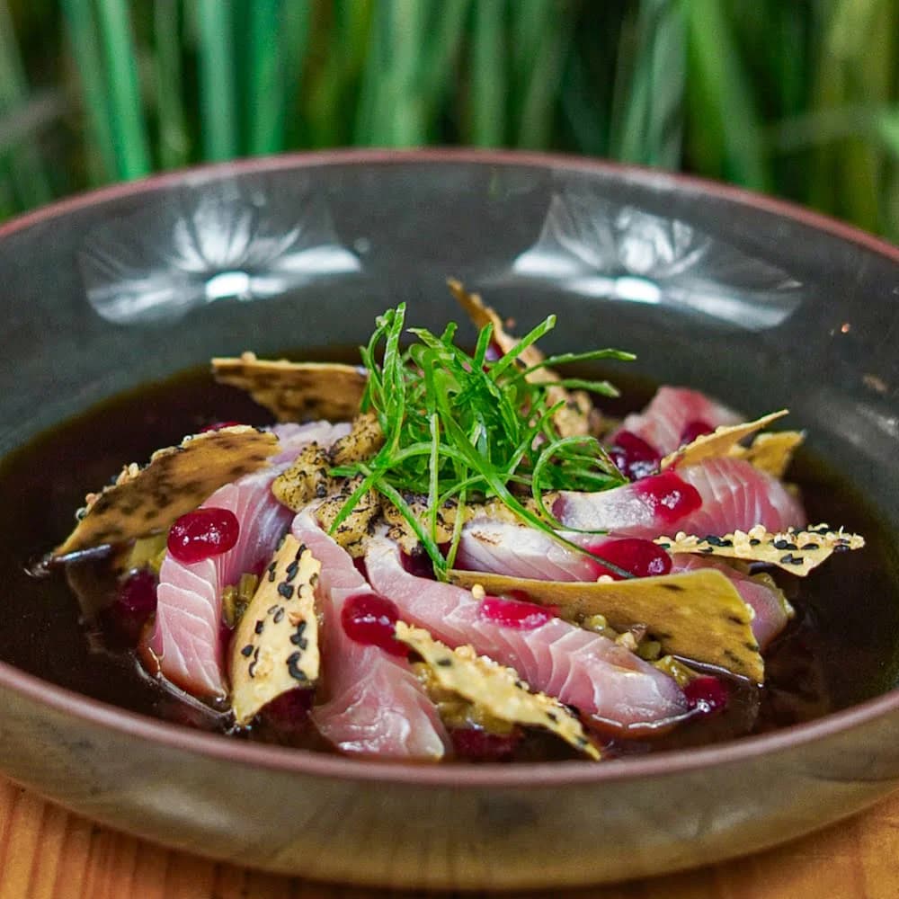 TIRADITO CON KATSUO SALSA PONZU, PACHIKAY, GEL DE HIBISCUS, CROCANTE CON SEMILLAS DE SÉSAMO, CHALAQUITA DE ULTE Y SHIITAKE.